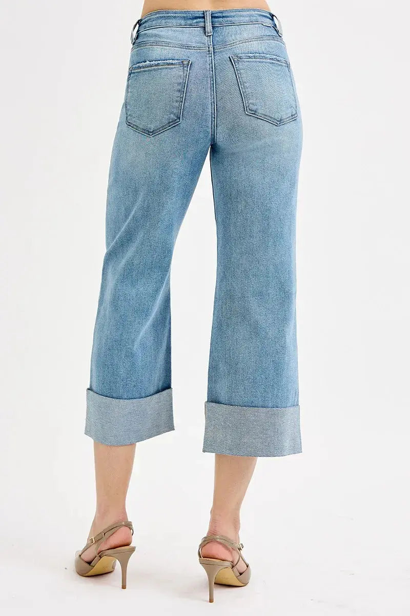 The back of light blue jeans with rolled-up cuffs on a white background