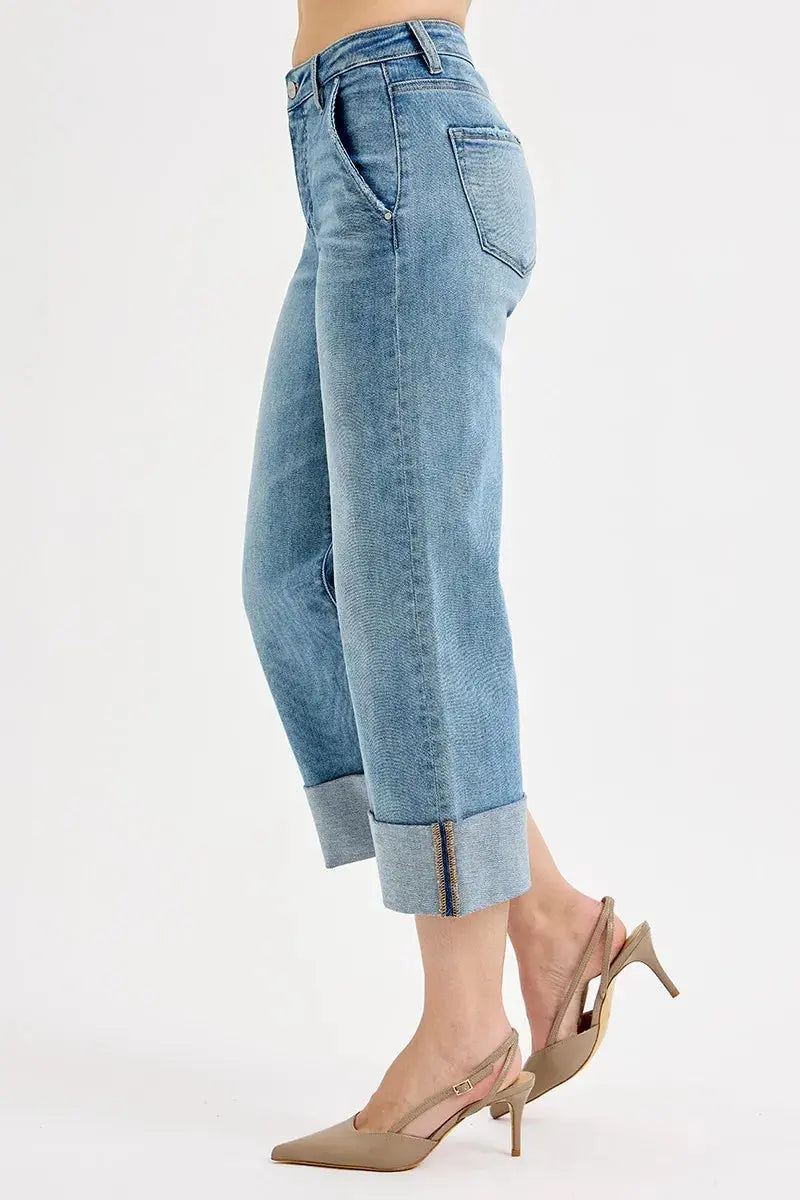 The side view of light blue cuffed jeans worn by a person on a white background