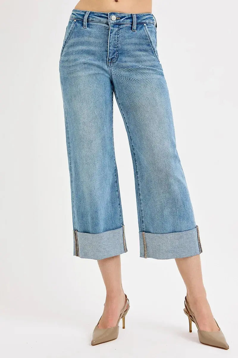 Blue jeans with rolled-up cuffs worn by a person on a white background