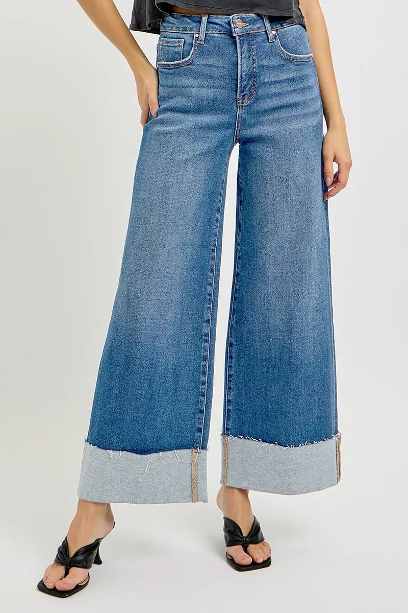 Wide-leg cuffed jeans with raw hems on a white background