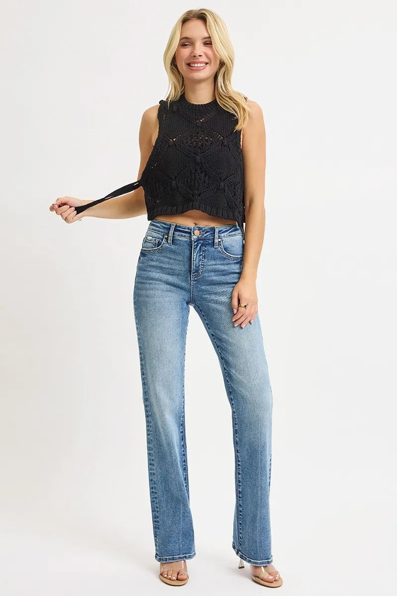 Woman wearing a black sleeveless top and light blue straight leg jeans on a white background