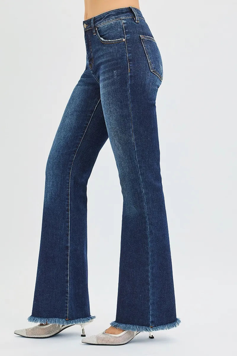 The side view of dark wash flared blue jeans worn by a person on a white background