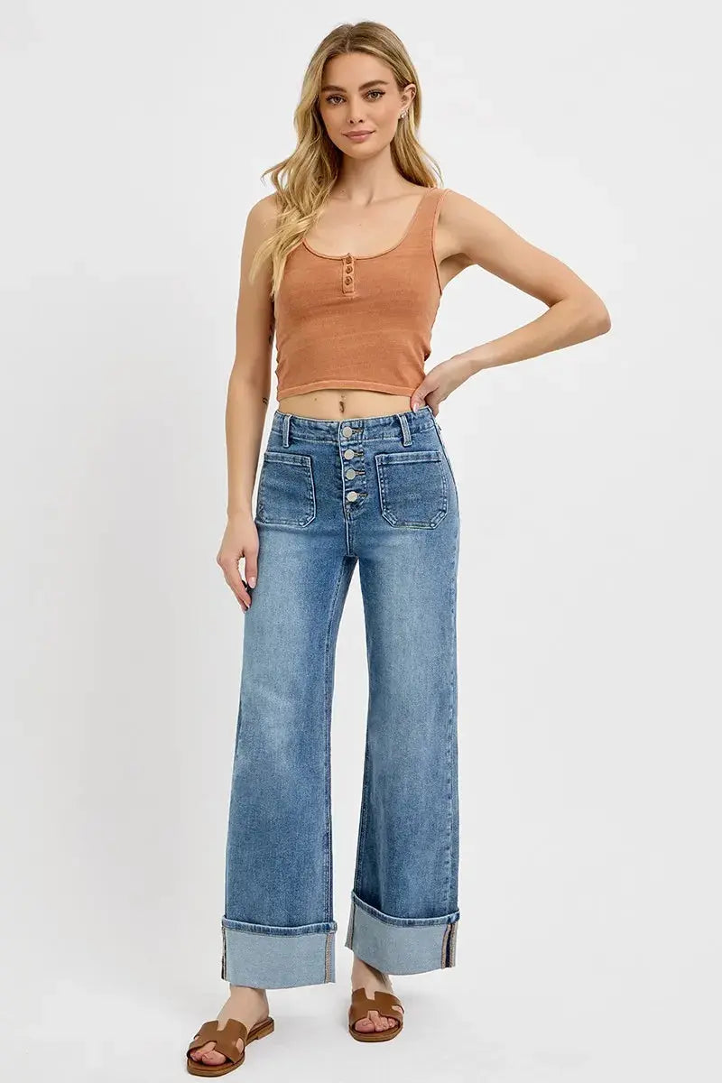 Woman wearing a brown tank top and wide leg blue jeans on a white background