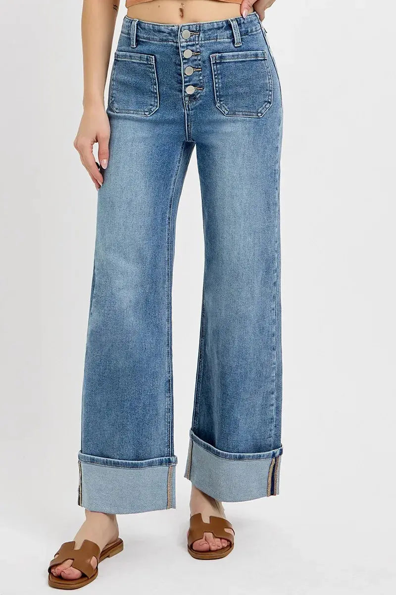 Wide leg, cuffed blue jeans with patch like pockets worn by a person on a white background