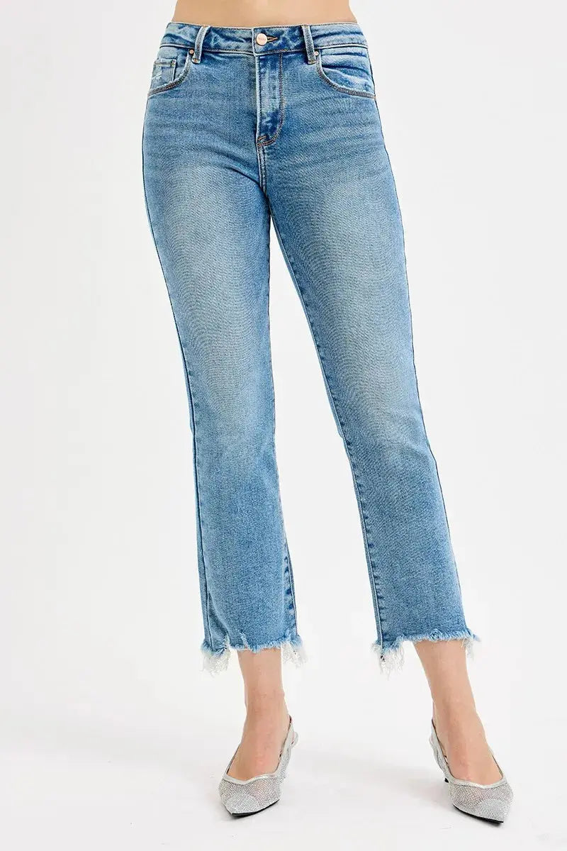 Light blue denim jeans worn by a person wearing white pointed toe shoes on a white background.