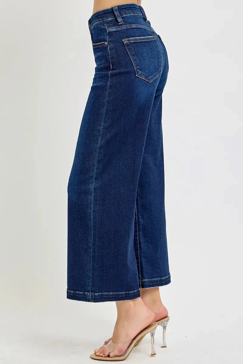 A side view of wide leg cropped blue jeans worn by a person on a white background