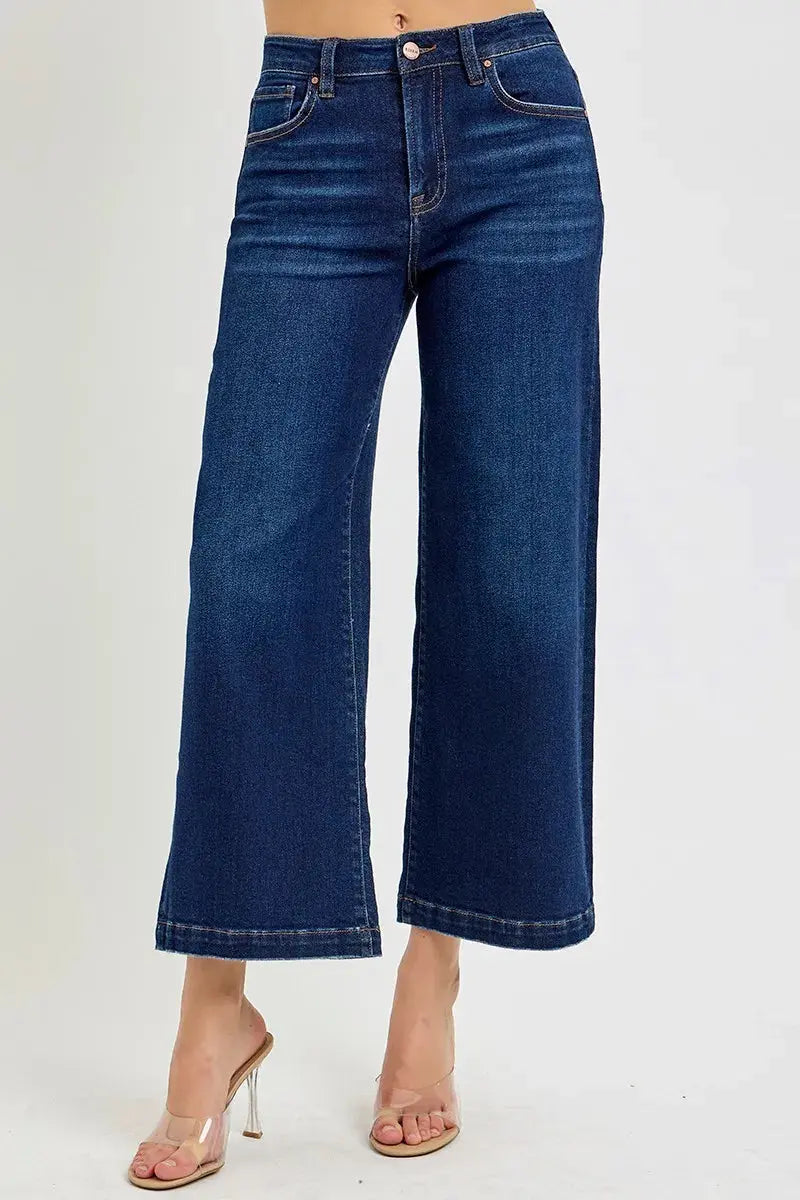 Dark wash, cropped, wide leg blue jeans worn by a person on a white background
