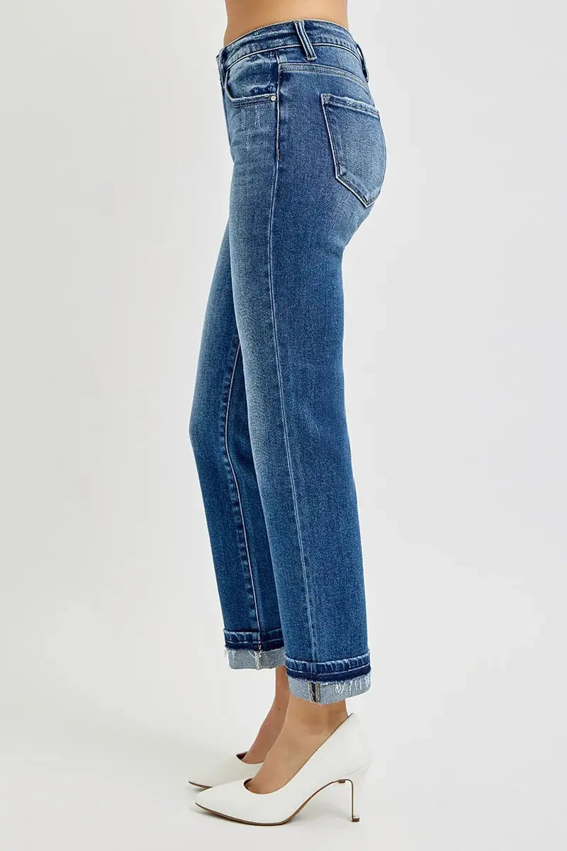 Cuffed and cropped blue jeans worn by a person on a white background