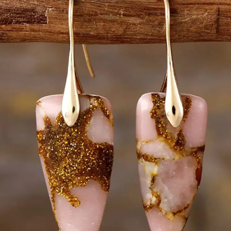 These raw stone drop earrings are featured on a rustic background.