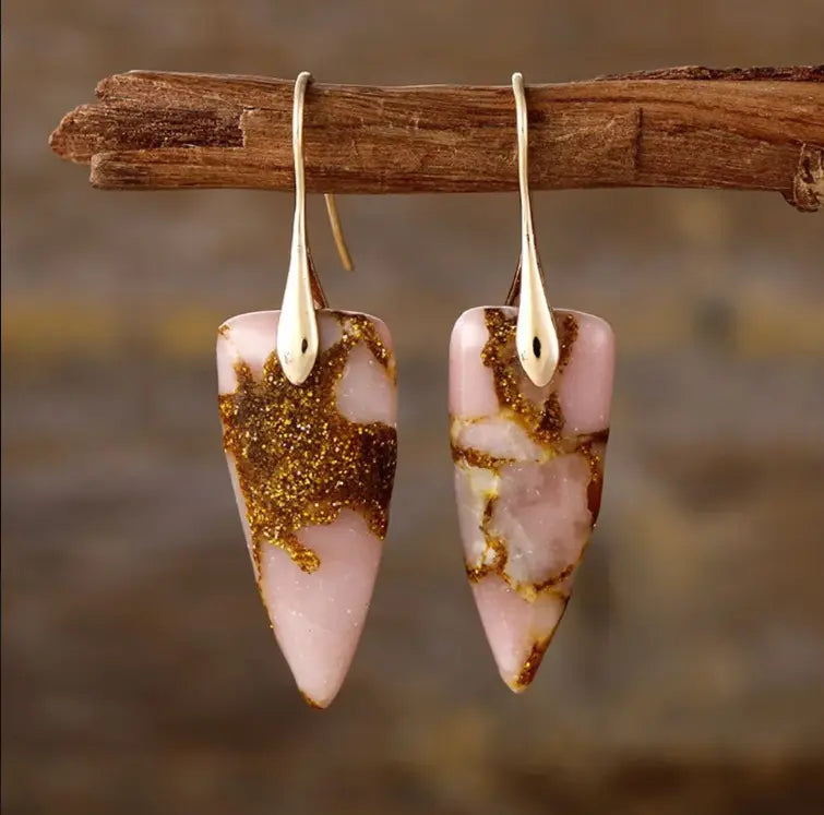 These raw stone drop earrings are featured on a rustic background.