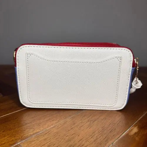 Channel the iconic style of Marc Jacobs with this Snapshot-inspired crossbody—a compact, structured silhouette that blends bold design with everyday function. Crafted from smooth faux leather, it features a dual-zip top closure and a color block palette that adds instant personality to any outfit.