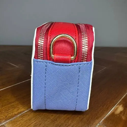 Channel the iconic style of Marc Jacobs with this Snapshot-inspired crossbody—a compact, structured silhouette that blends bold design with everyday function. Crafted from smooth faux leather, it features a dual-zip top closure and a color block palette that adds instant personality to any outfit.