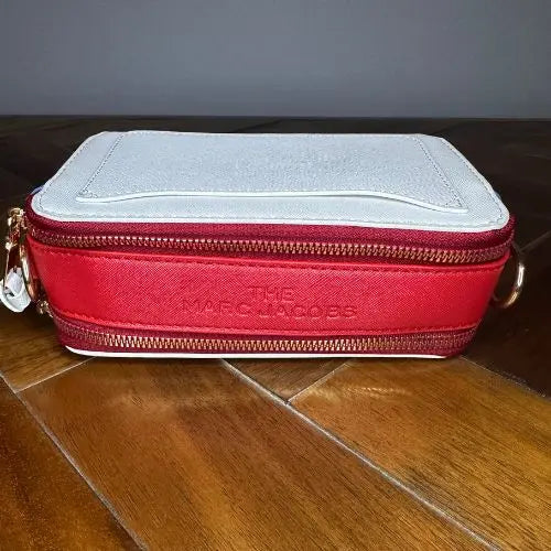 Channel the iconic style of Marc Jacobs with this Snapshot-inspired crossbody—a compact, structured silhouette that blends bold design with everyday function. Crafted from smooth faux leather, it features a dual-zip top closure and a color block palette that adds instant personality to any outfit.