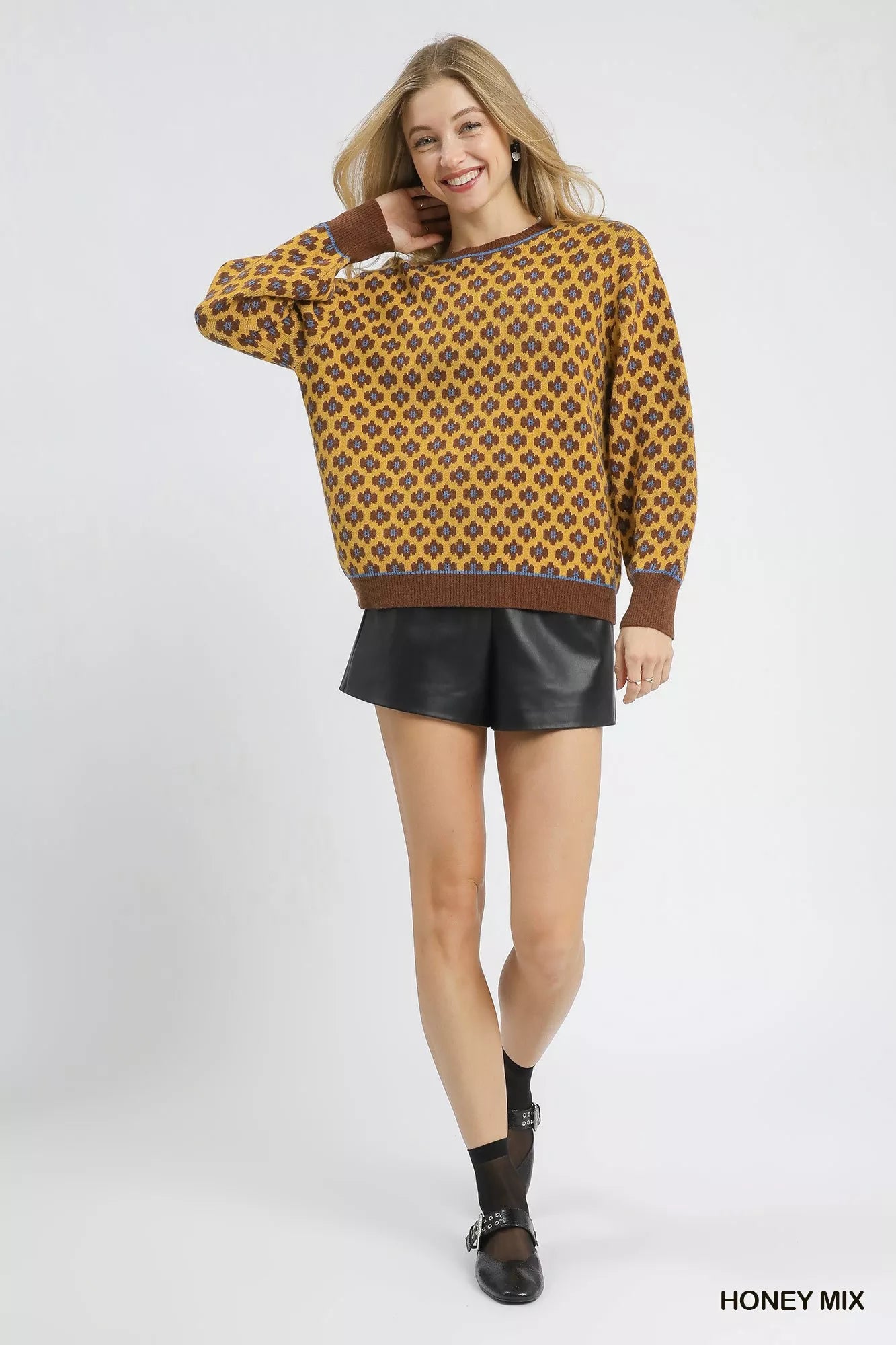 Woman wearing a patterned sweater with a honey mix color on a white background