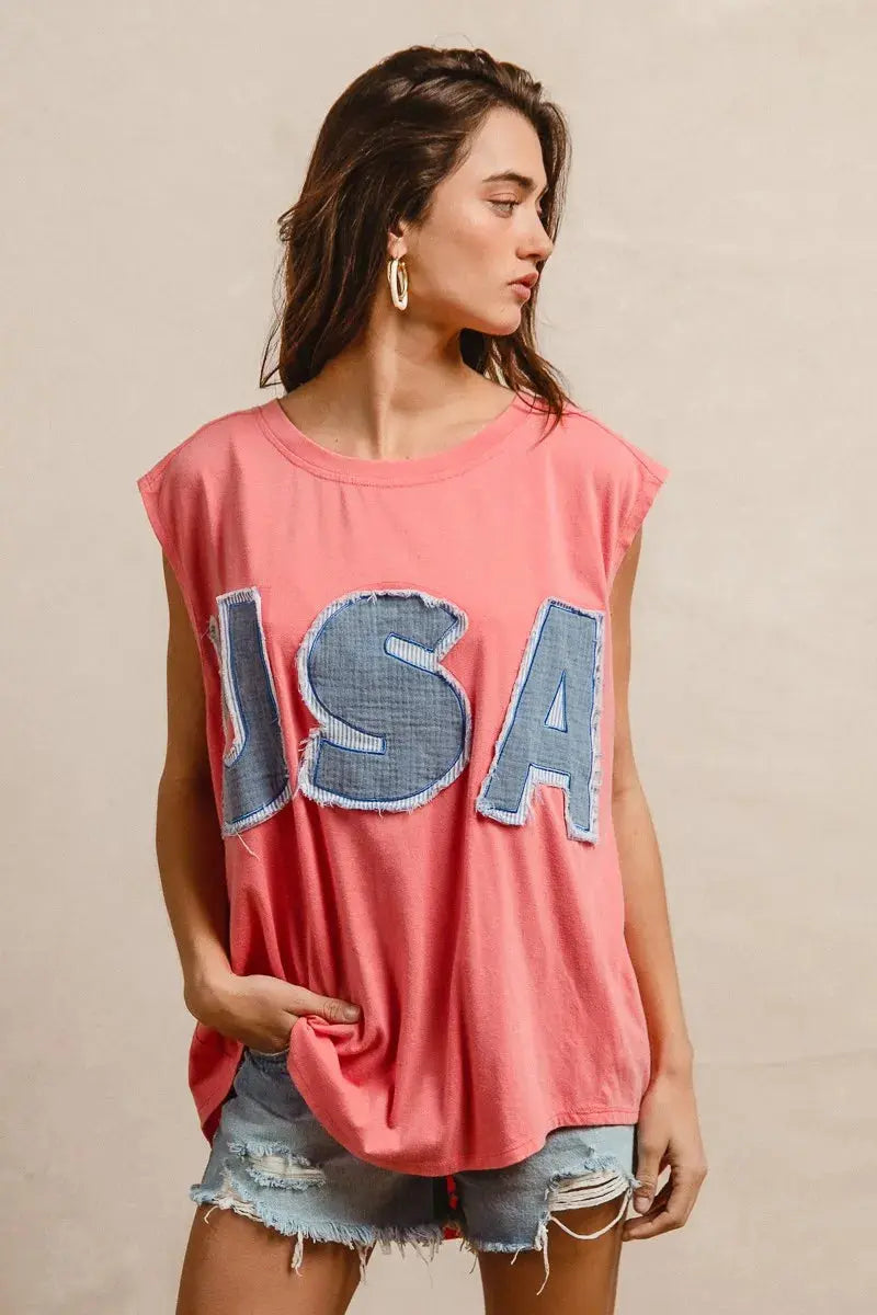 This fashion USA graphic t-shirt features a vibrant coral pink base with bold denim-style USA lettering across the chest. Made from soft cotton blend fabric for ultimate comfort and breathability. The relaxed oversized fit provides a casual, effortless look perfect for everyday wear. The vintage-inspired patriotic design makes it ideal for summer festivals, casual outings, or showing American pride. The round neckline and loose silhouette offer versatile styling options for pairing with jeans, shorts, etc.