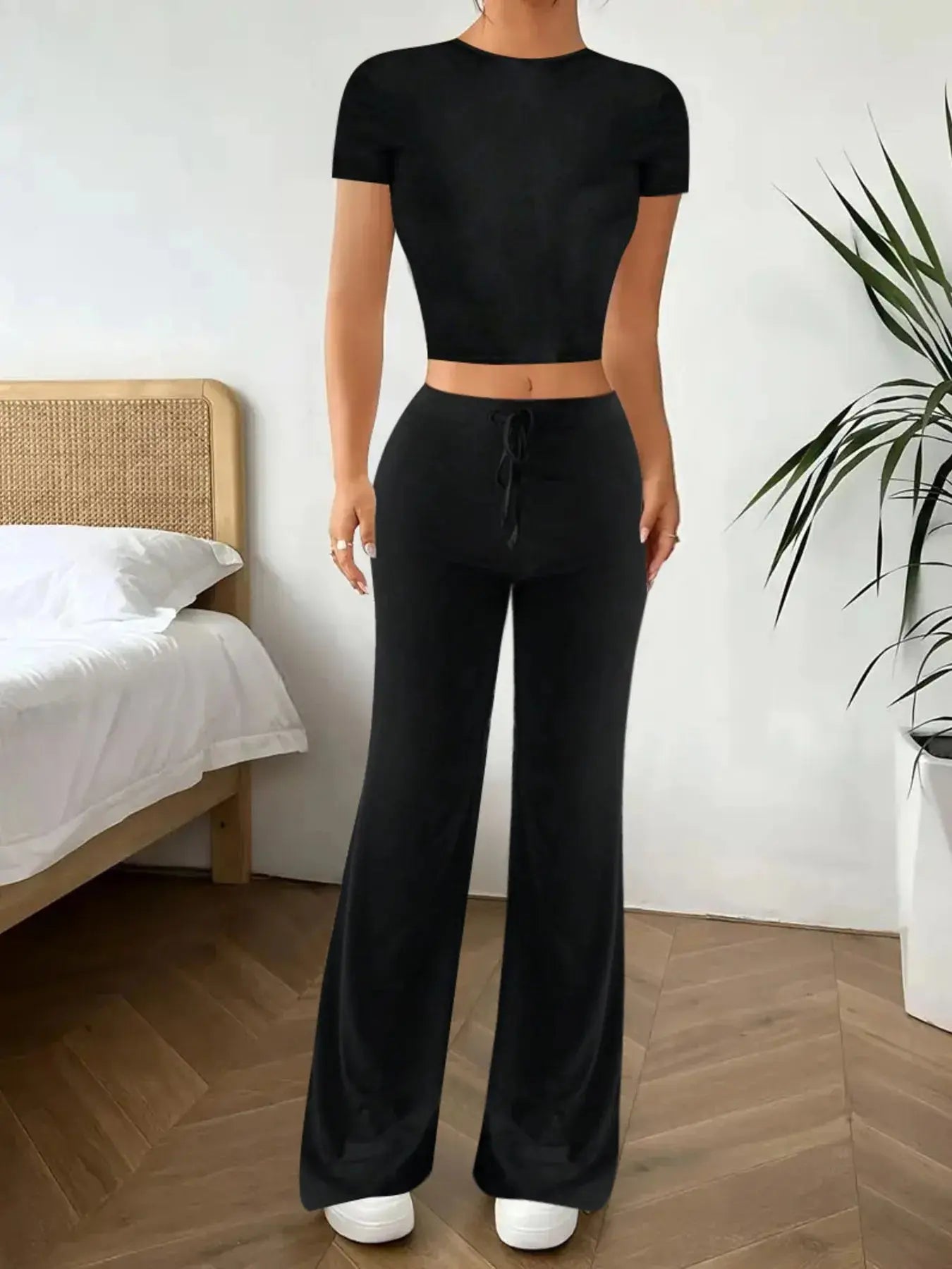 Elevate your off-duty wardrobe with this sleek black two-piece set, featuring a fitted crop top and high-waisted wide-leg pants. The top hugs your frame with a flattering silhouette, while the flowy pants offer all-day comfort and movement. Whether you're lounging at home or heading out for errands, this ensemble delivers polished ease with minimal effort.