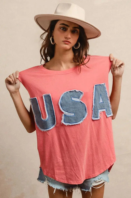 This fashion USA graphic t-shirt features a vibrant coral pink base with bold denim-style USA lettering across the chest. Made from soft cotton blend fabric for ultimate comfort and breathability. The relaxed oversized fit provides a casual, effortless look perfect for everyday wear. The vintage-inspired patriotic design makes it ideal for summer festivals, casual outings, or showing American pride. The round neckline and loose silhouette offer versatile styling options for pairing with jeans, shorts, etc. 