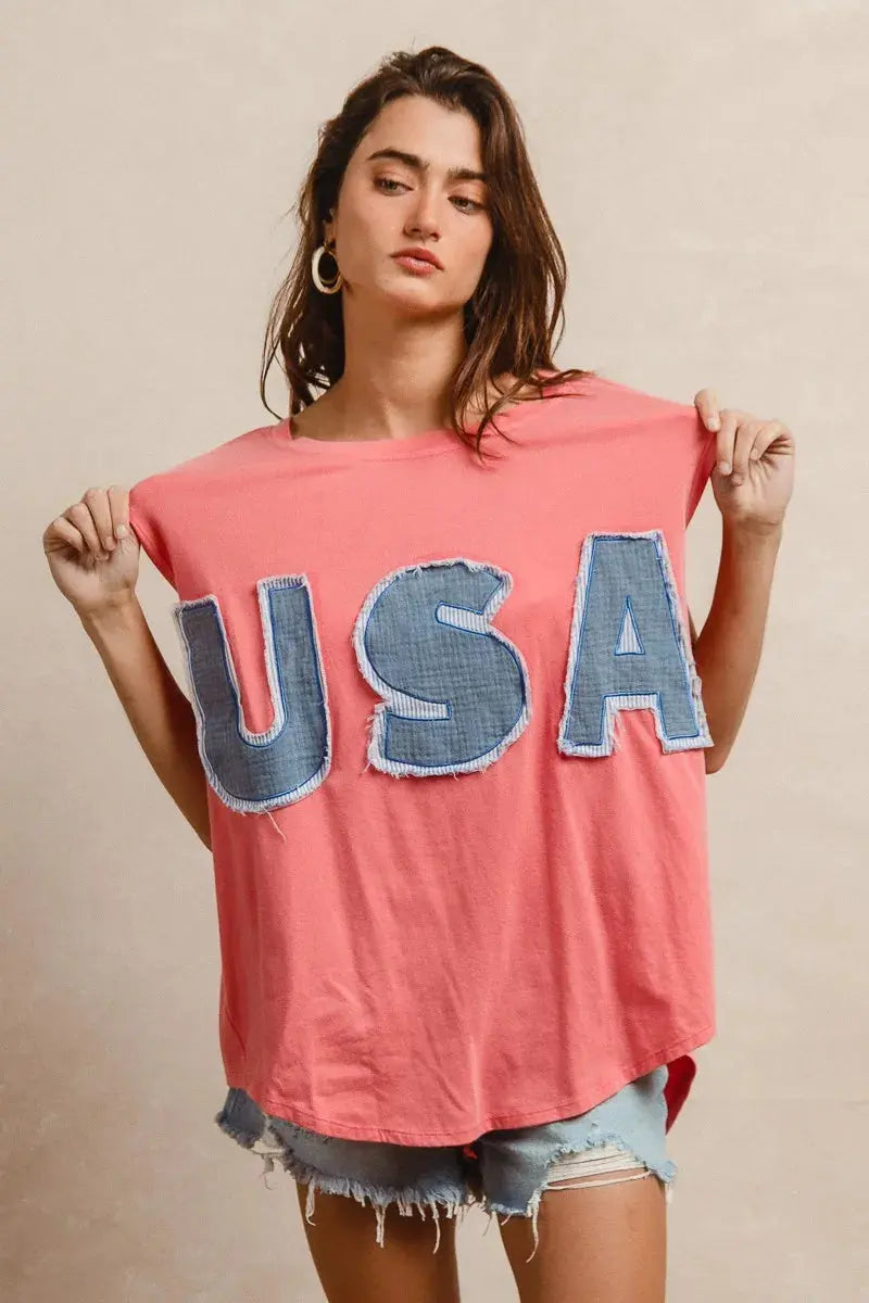 This fashion USA graphic t-shirt features a vibrant coral pink base with bold denim-style USA lettering across the chest. Made from soft cotton blend fabric for ultimate comfort and breathability. The relaxed oversized fit provides a casual, effortless look perfect for everyday wear. The vintage-inspired patriotic design makes it ideal for summer festivals, casual outings, or showing American pride. The round neckline and loose silhouette offer versatile styling options for pairing with jeans, shorts, etc. 