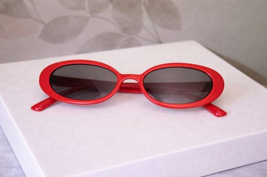 Red sunglasses on a white surface with a neutral background