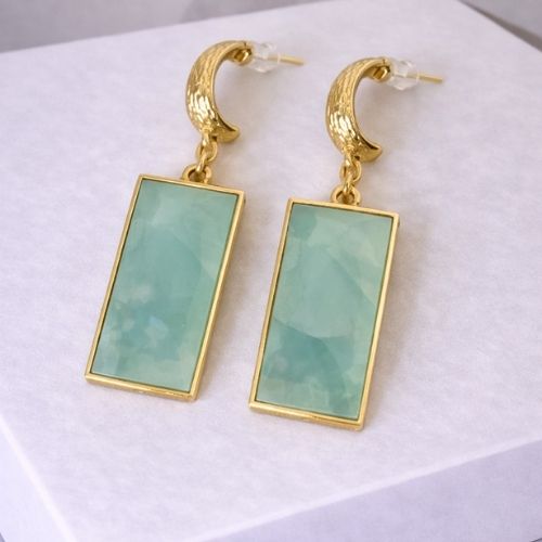 Gold earrings with green rectangular stones on a white background