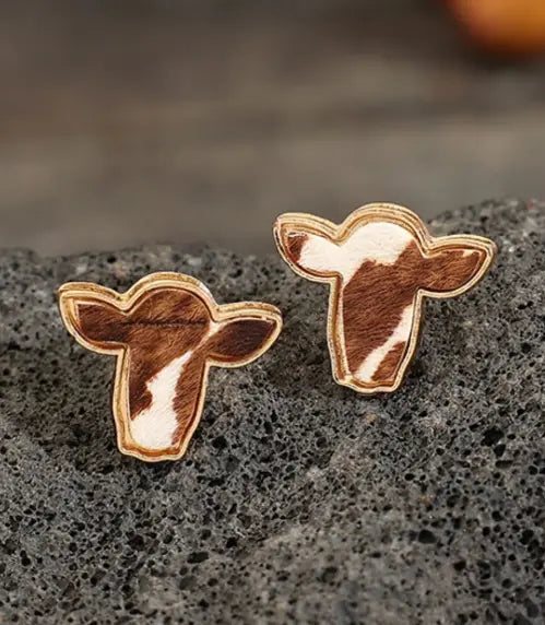 pair of bold boho cowhide stud earrings on rustic background. 