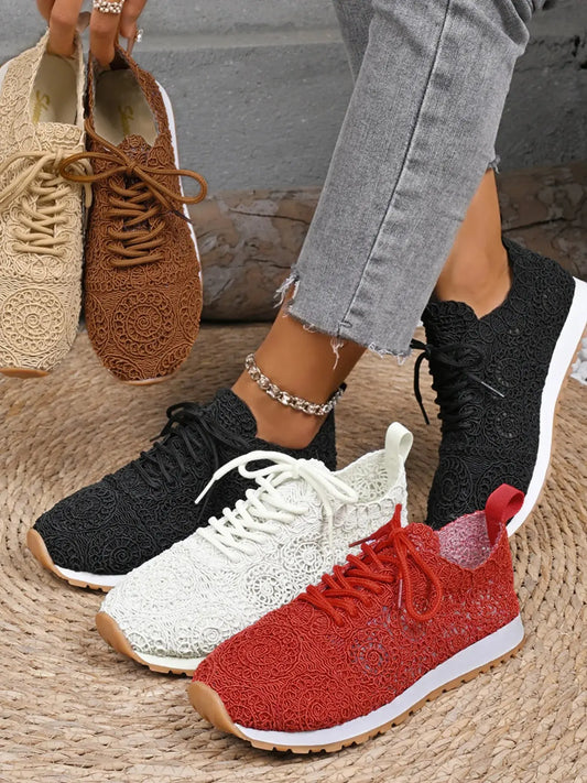 Four pairs of sneakers in different colors on a textured surface.