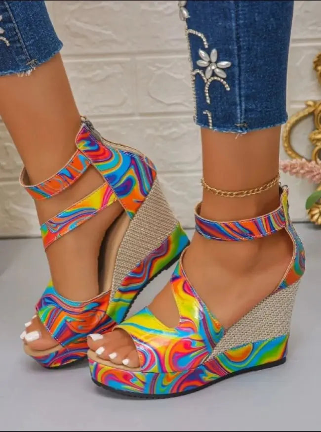 Colorful wedge sandals with a pattern worn with blue jeans.
