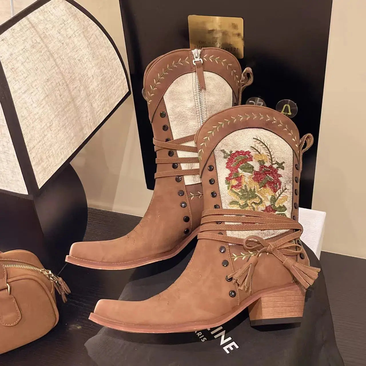 Brown cowboy boots with floral embroidery on a dark surface.
