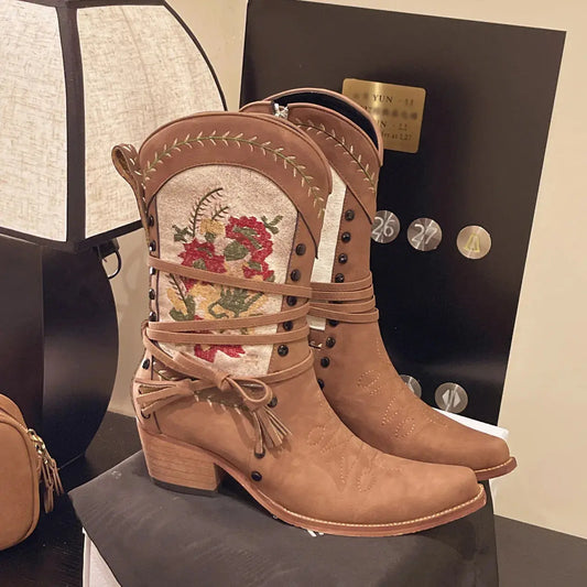 Brown embroidered boots on a black surface.