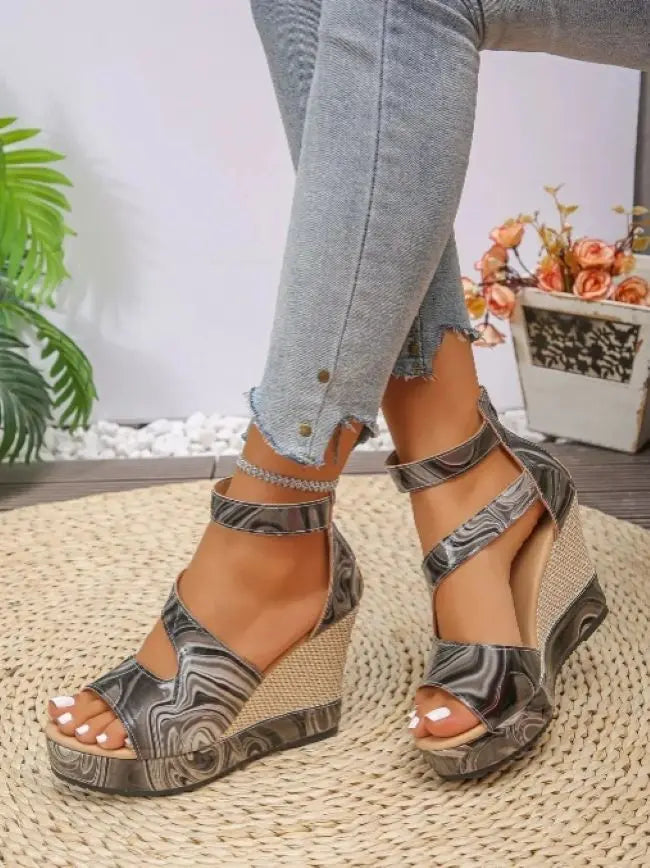 Marbled wedge sandals worn with light blue jeans on a textured surface.
