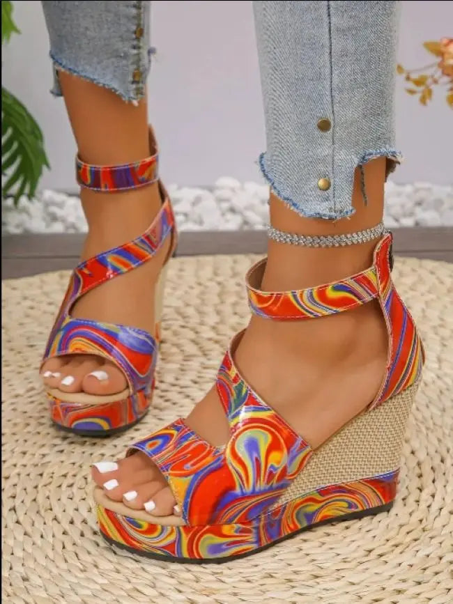 Colorful wedge sandals worn with denim jeans on a woven surface.