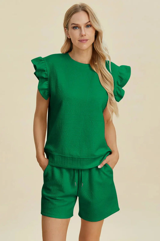 Woman wearing a textured green set with ruffled sleeves on a beige background.