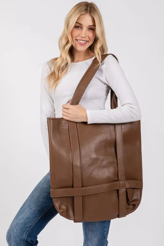Woman holding a large brown tote bag against a white background.
