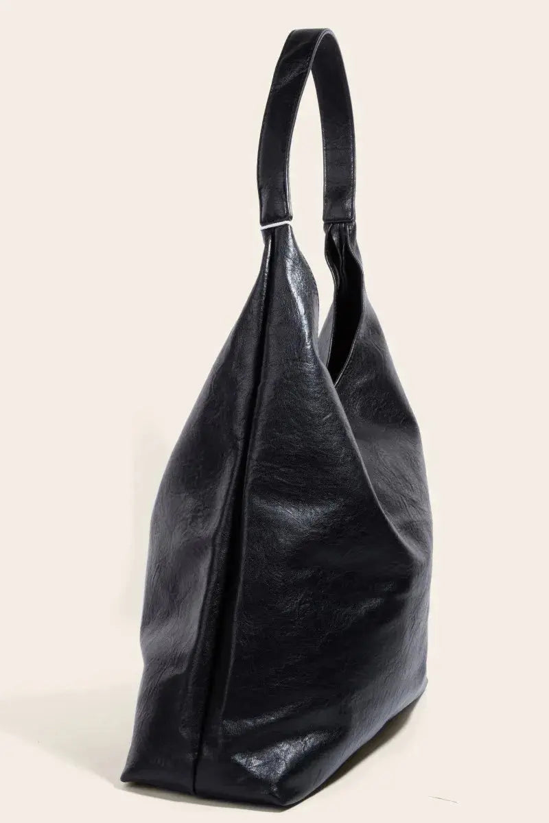 The side view of a black faux leather handbag on a light beige background.