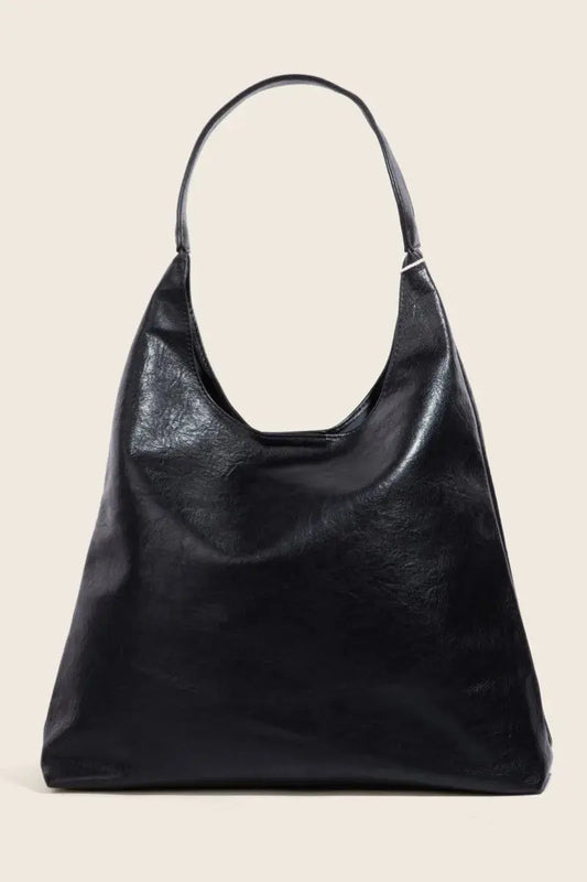 Black faux leather handbag on a beige background.