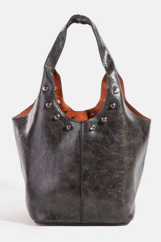 Black faux leather handbag with brown interior and decorative studs on a white background.