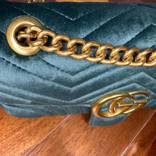 Green handbag with gold chain detail on a wooden surface