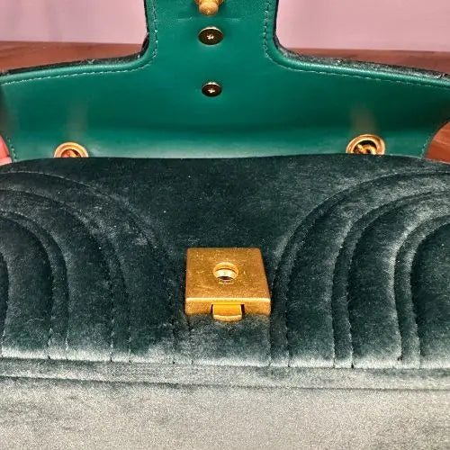 Close-up of a green handbag with gold hardware.
