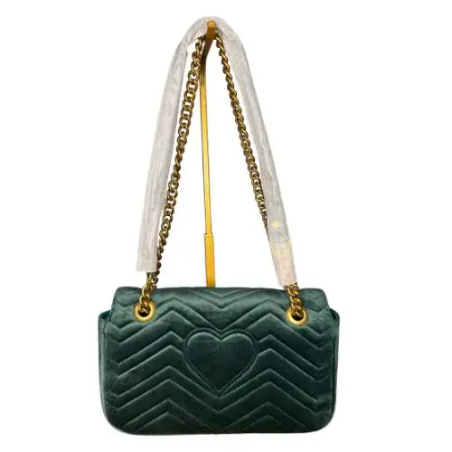 Green quilted handbag with gold chain strap on a white background