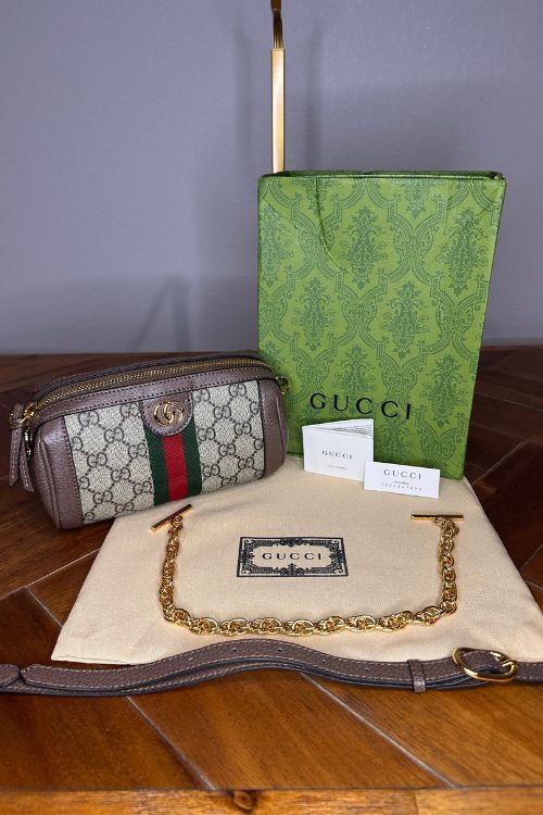 Gucci handbag with green box and dust bag on a wooden surface