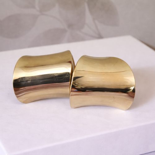 Gold Cuff Earrings on White Box with Flower Background
