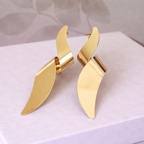 Gold wing-shaped earrings on a white surface