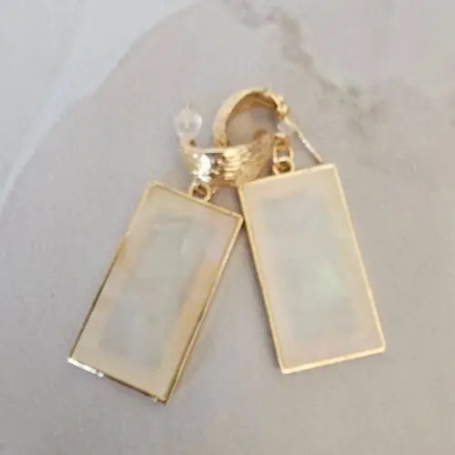 Close-up of gold hoop earrings with rectangular opal-inspired pendants and glossy finish — women’s boutique jewelry from Atlas by J&D.