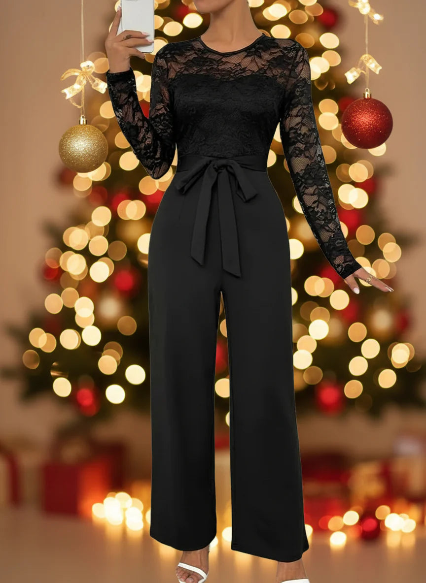 Black lace jumpsuit worn by a person against a white wall