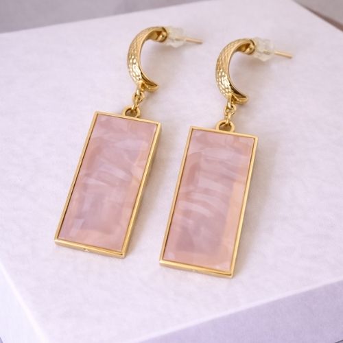 Gold earrings with pink stone on a white background