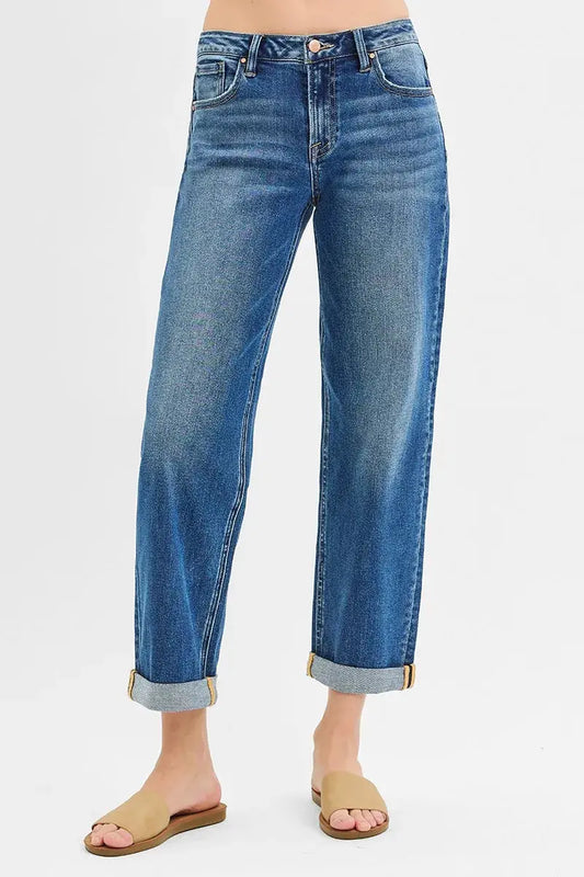 Cuffed and cropped blue jeans worn by a person on a light gray background.