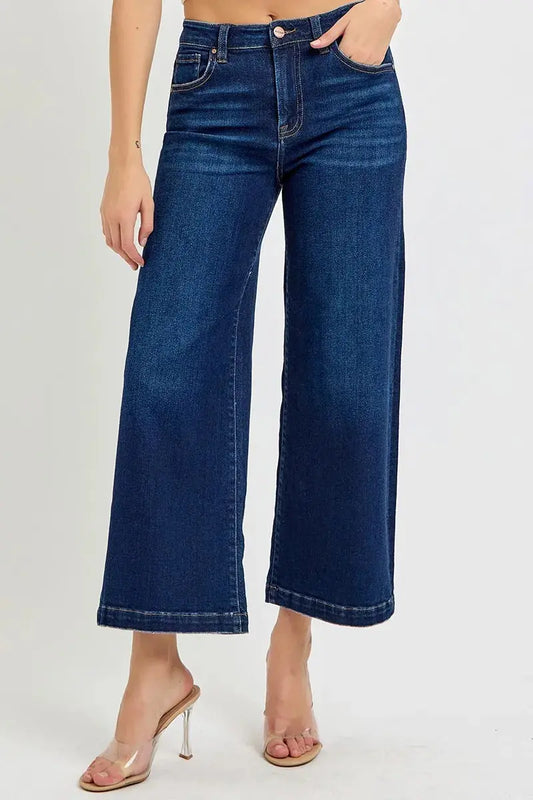 Person wearing dark wash, wide leg, cropped blue jeans on a white background