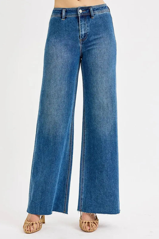 Wide leg blue jeans with raw hem on a white background.