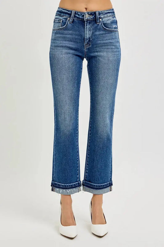 Cropped blue jeans worn by a person on a white background.