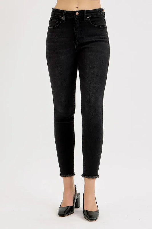Cropped black jeans worn by a person on a white background.